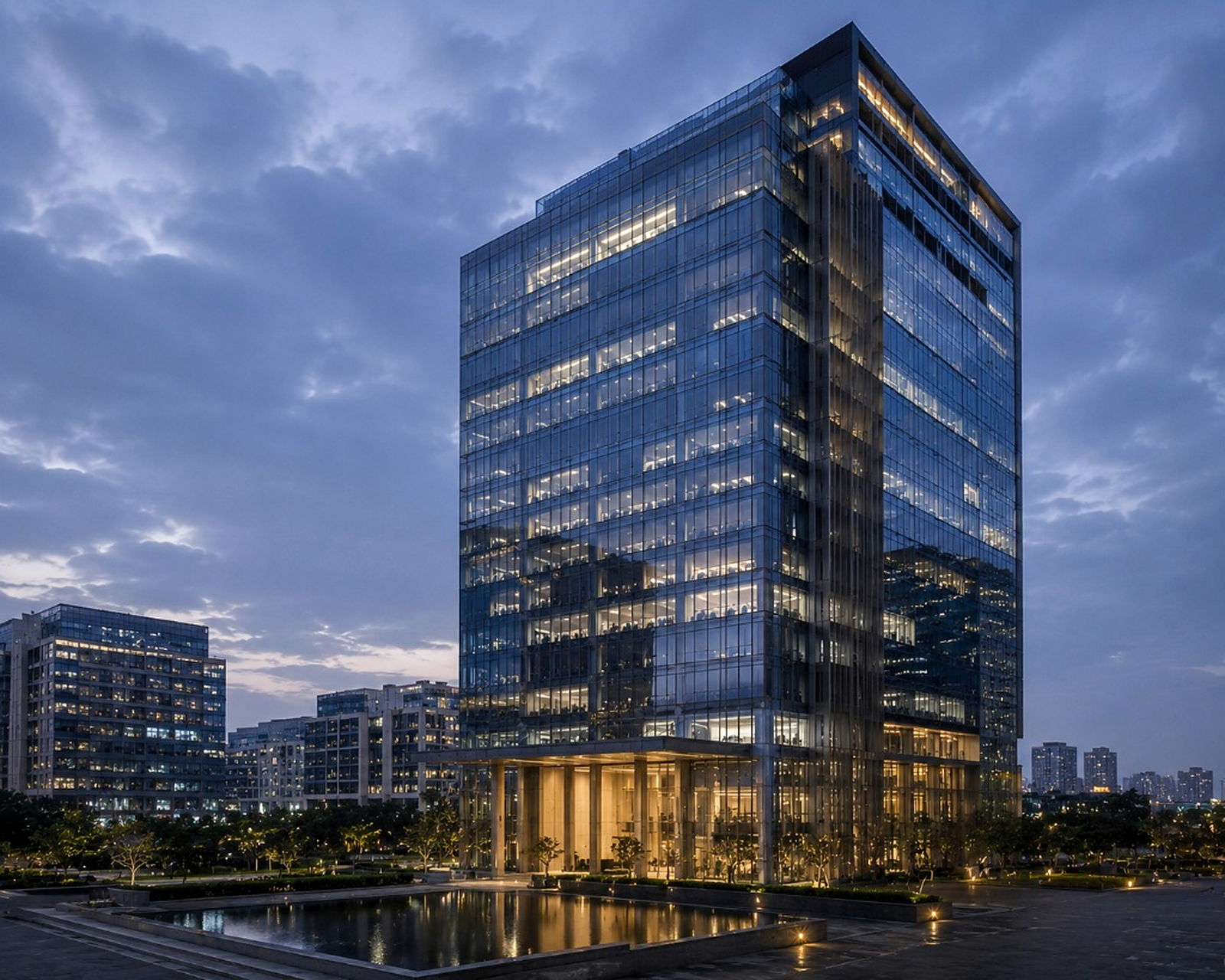 Modern glass commercial tower illuminated at dusk.